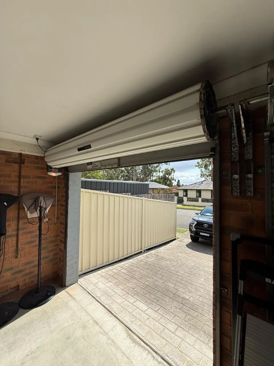 Interior garage view under open roller garage door looking outside